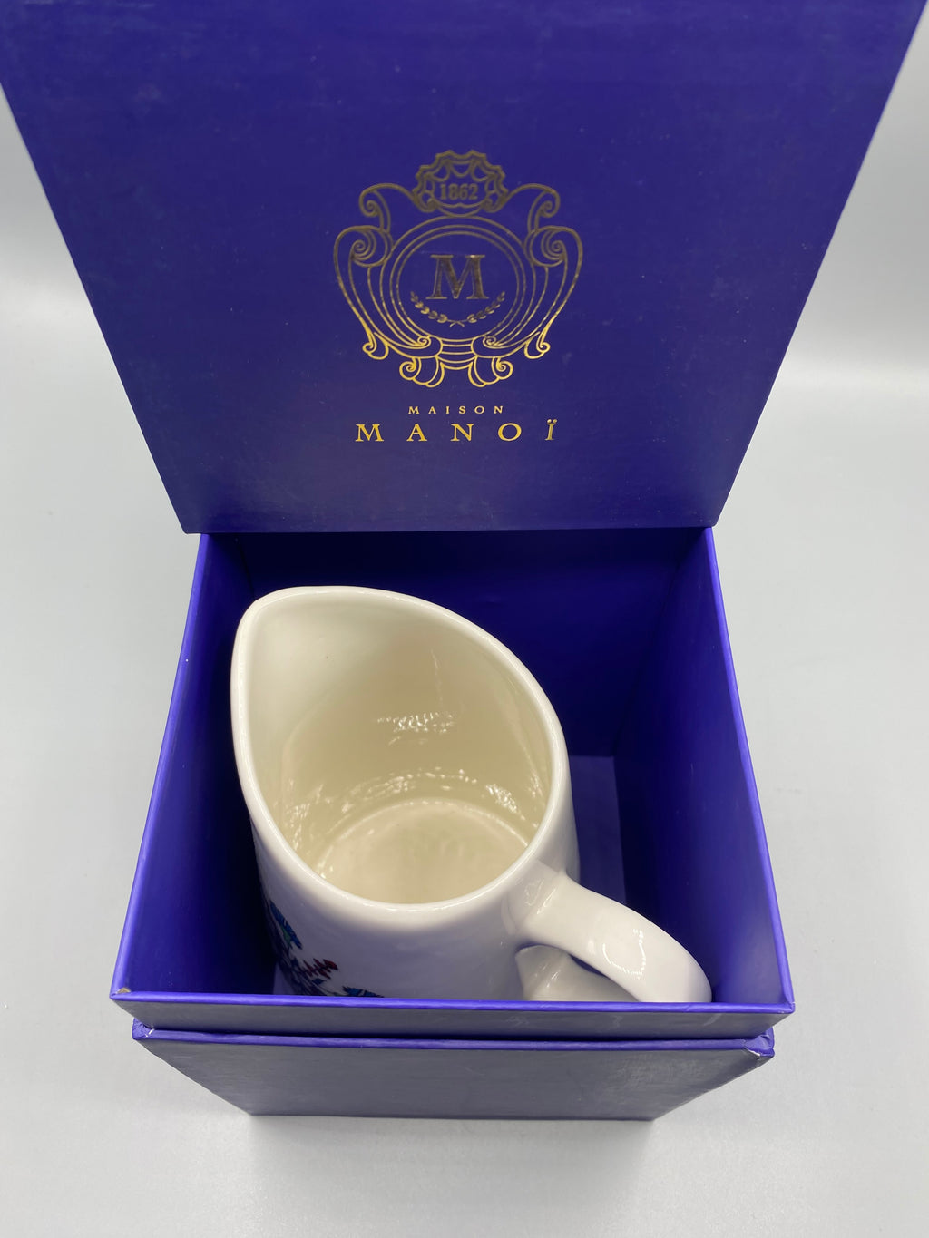 Pichet Maison Manoï dans son coffret bleu profond ouvert – doublure bleue blason doré