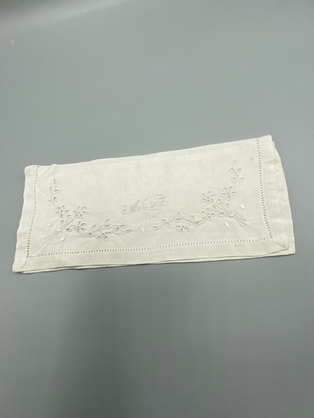 Détail broderie prénom Anne en cursive blanche – motif floral et jours à fils tirés