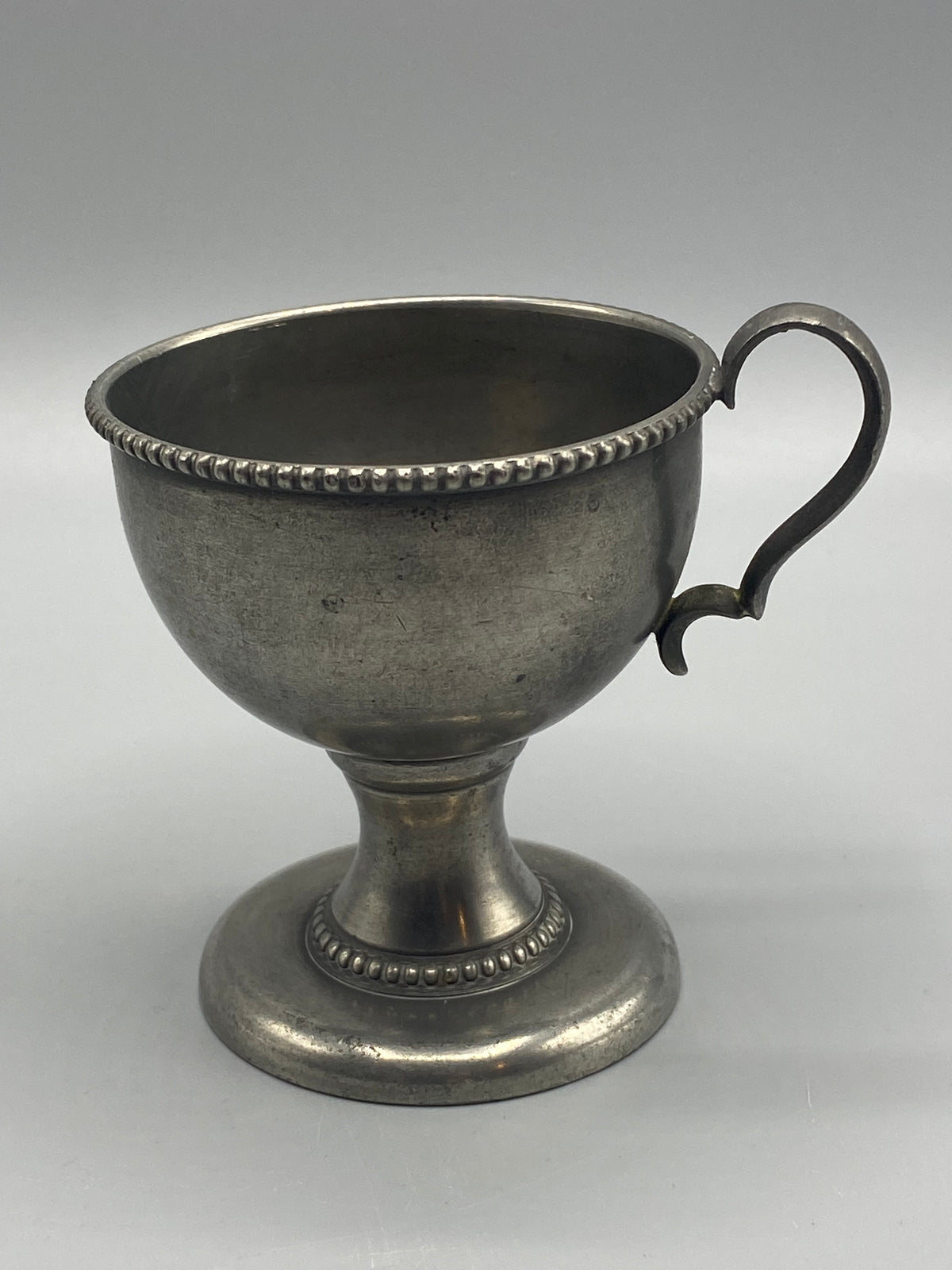 Tasse étain piédouche – vue trois quarts face anse et décor perlé