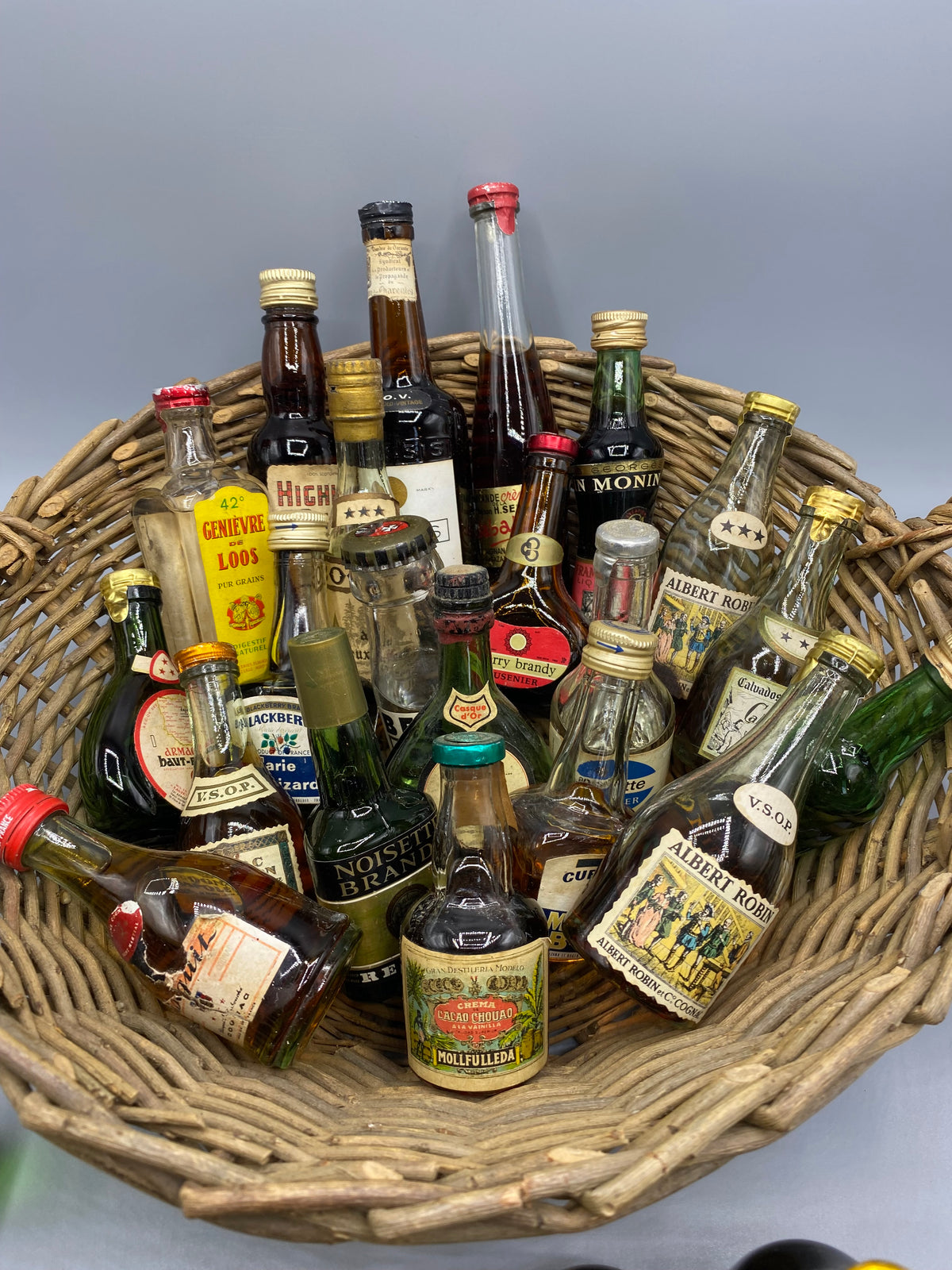 32 mignonnettes anciennes de spiritueux – Vue trois quarts panier plein, Grand Marnier et Pineau St-Martin visibles