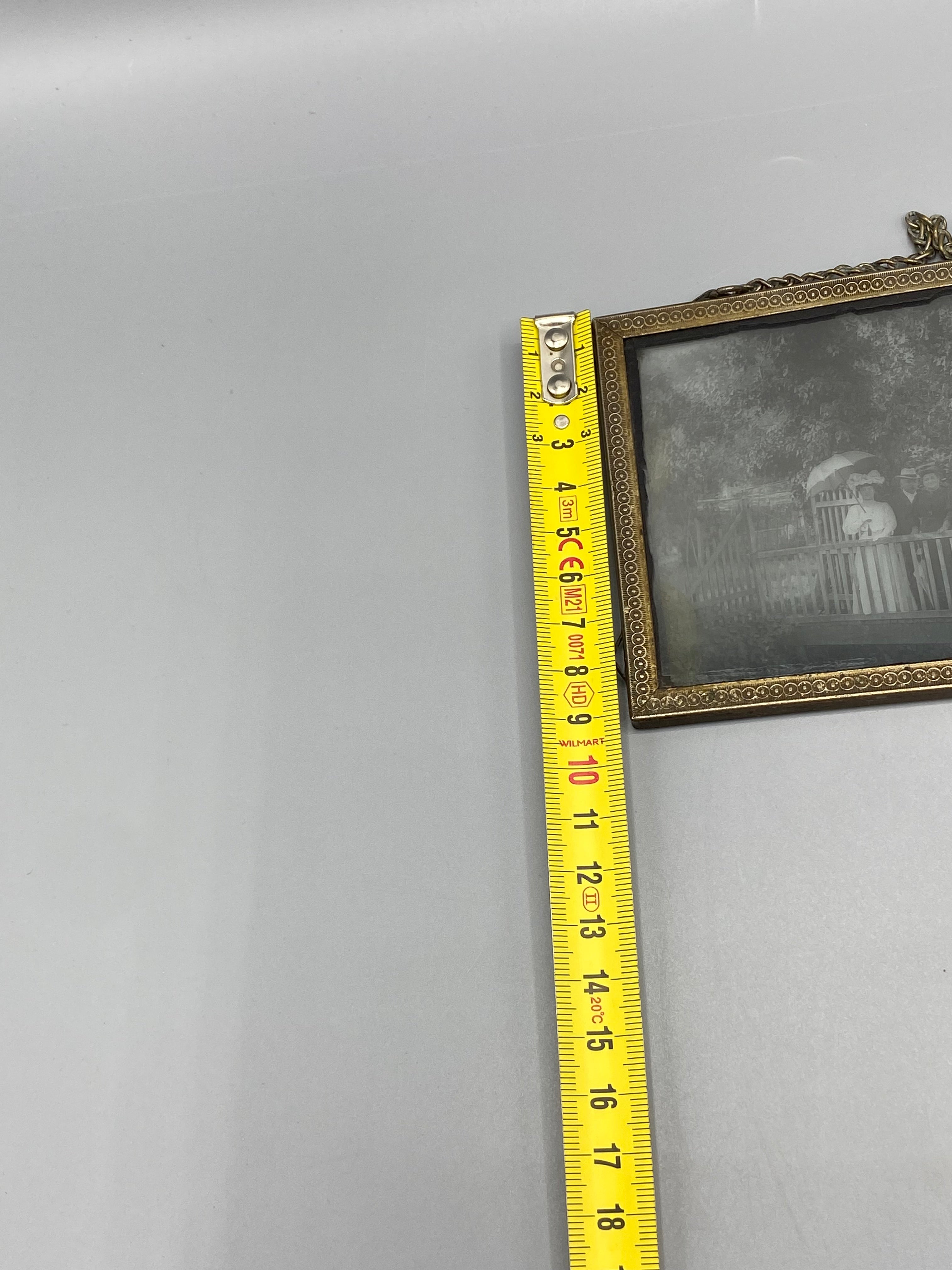 Détail de la frise estampiée en laiton doré et de la chaînette de suspension, cadre horizontal