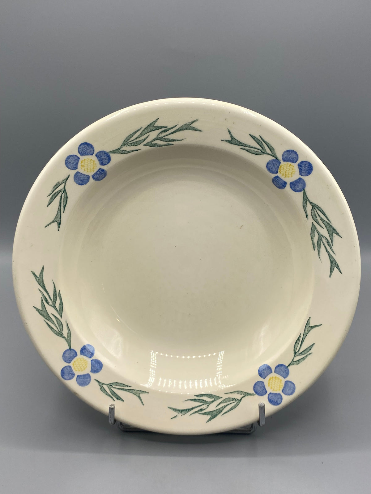 Plat creux ancien en faïence ivoire à décor de fleurs bleues, vue générale
