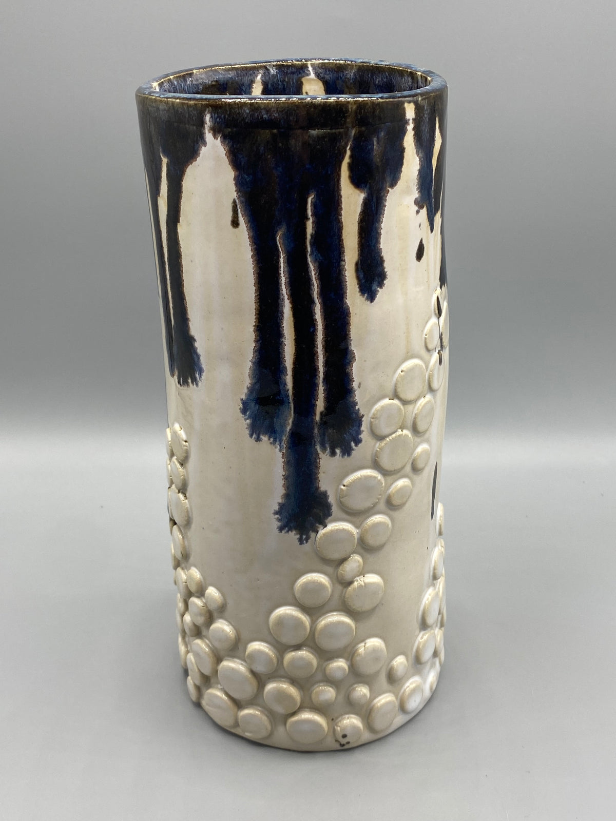 Coulures bleu profond et reliefs ivoire sur le vase en céramique