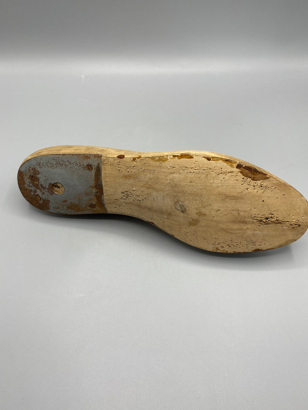 Dessous usé et plaque métallique au talon de la forme en bois