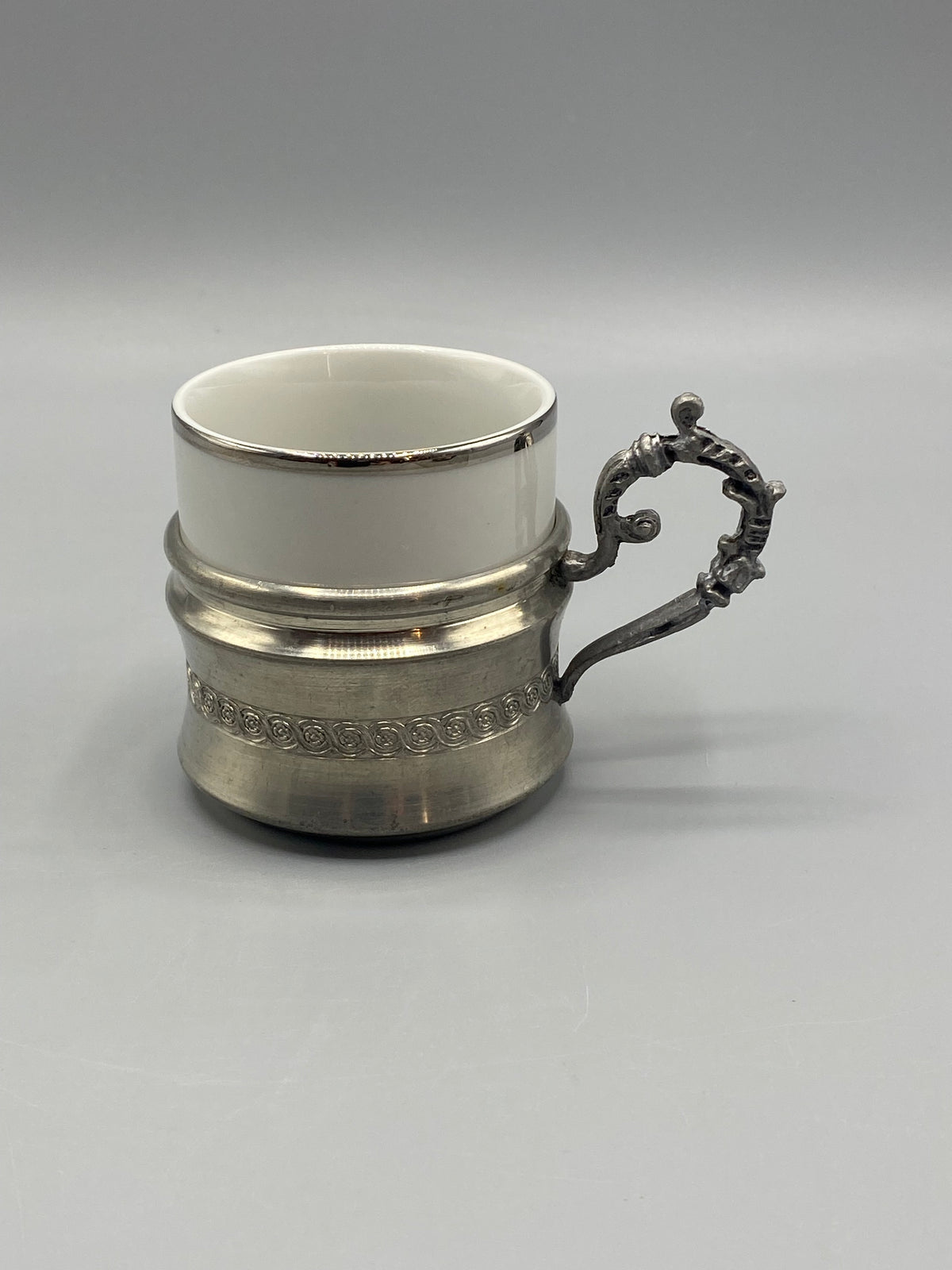 Détail de l’anse ajourée rocaille de la tasse en porcelaine et étain