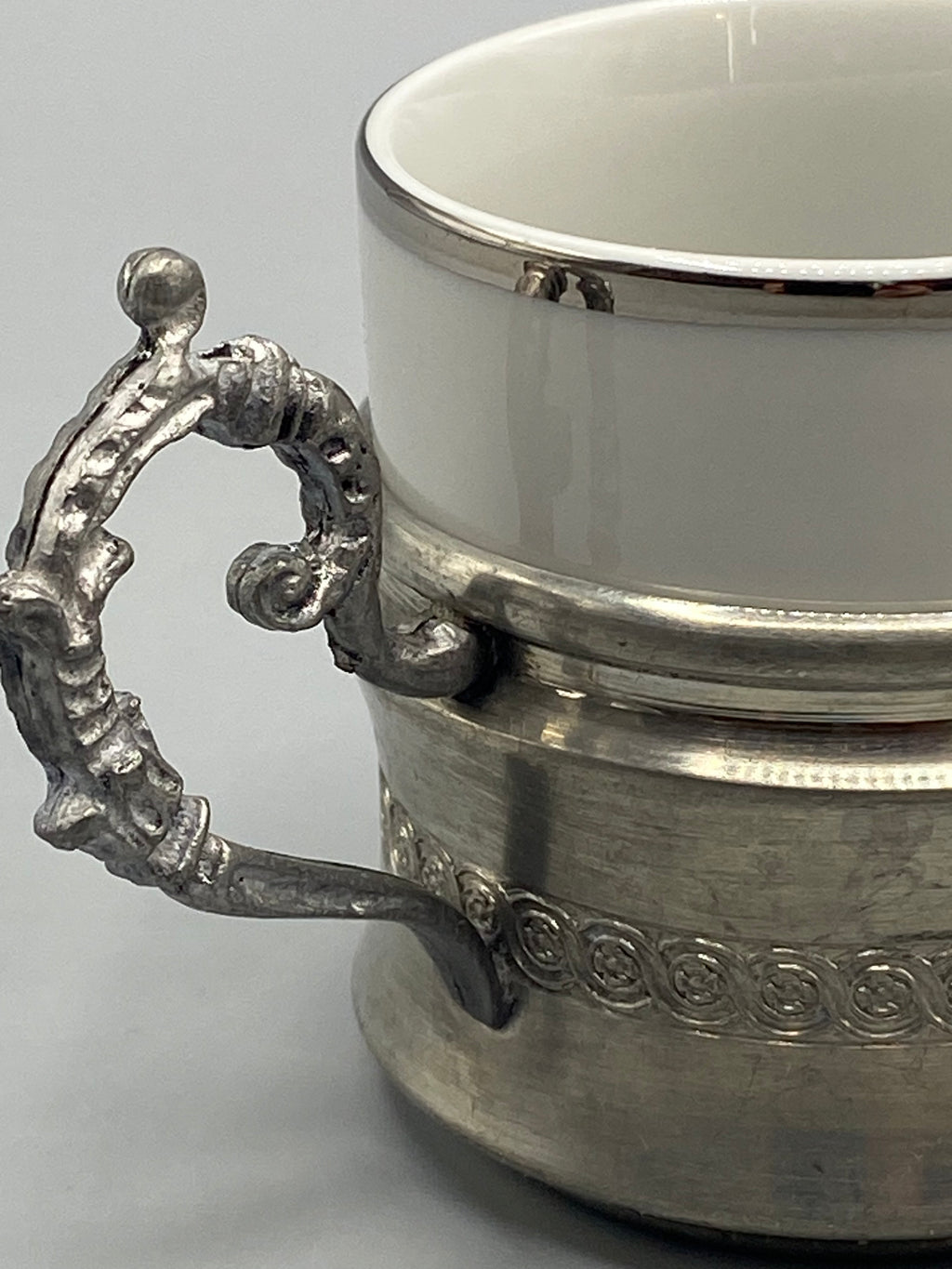 Tasse en porcelaine blanche retirée de sa monture en étain patiné