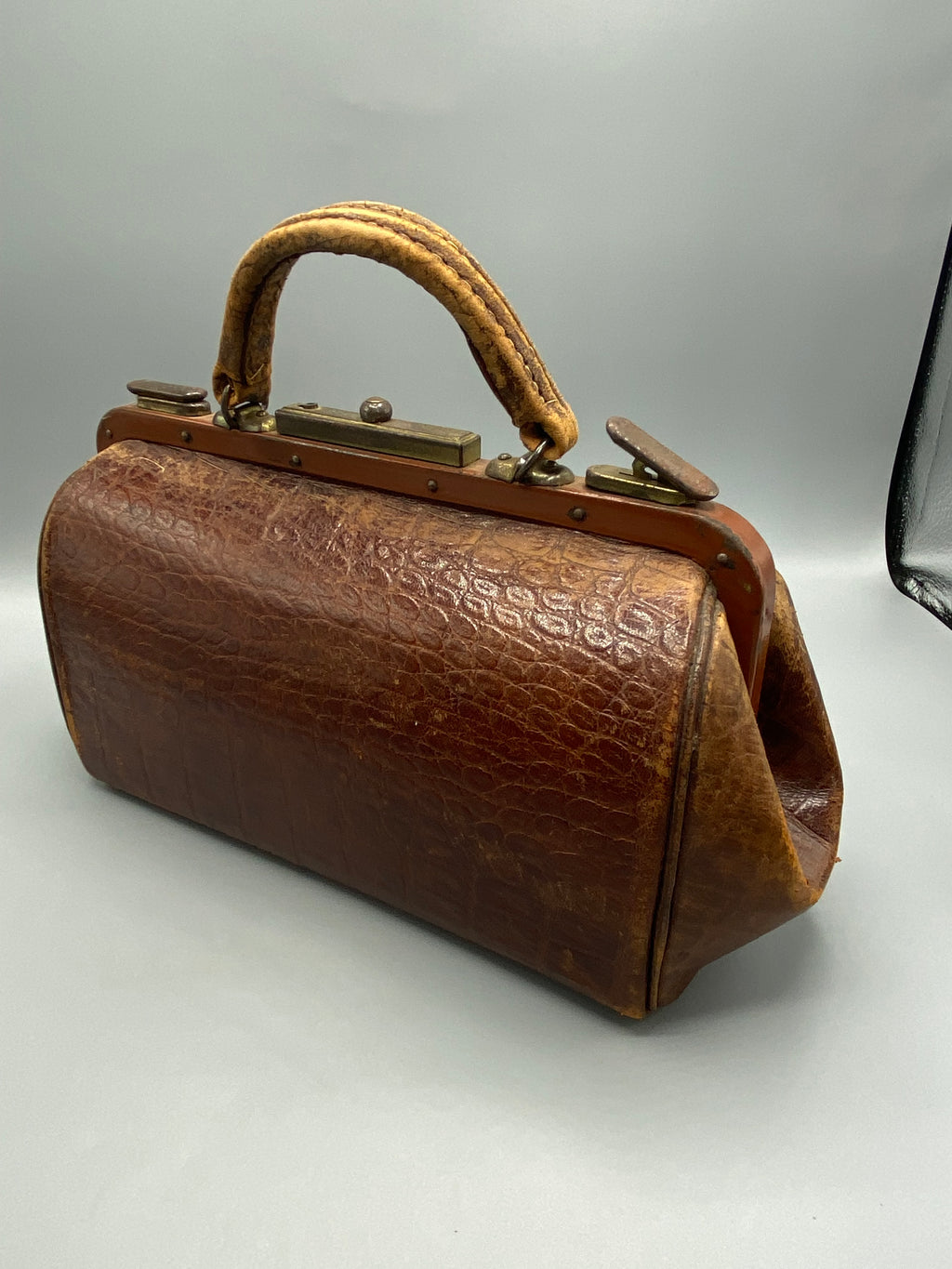 Détail du fermoir métallique et du cuir patiné du sac Gladstone