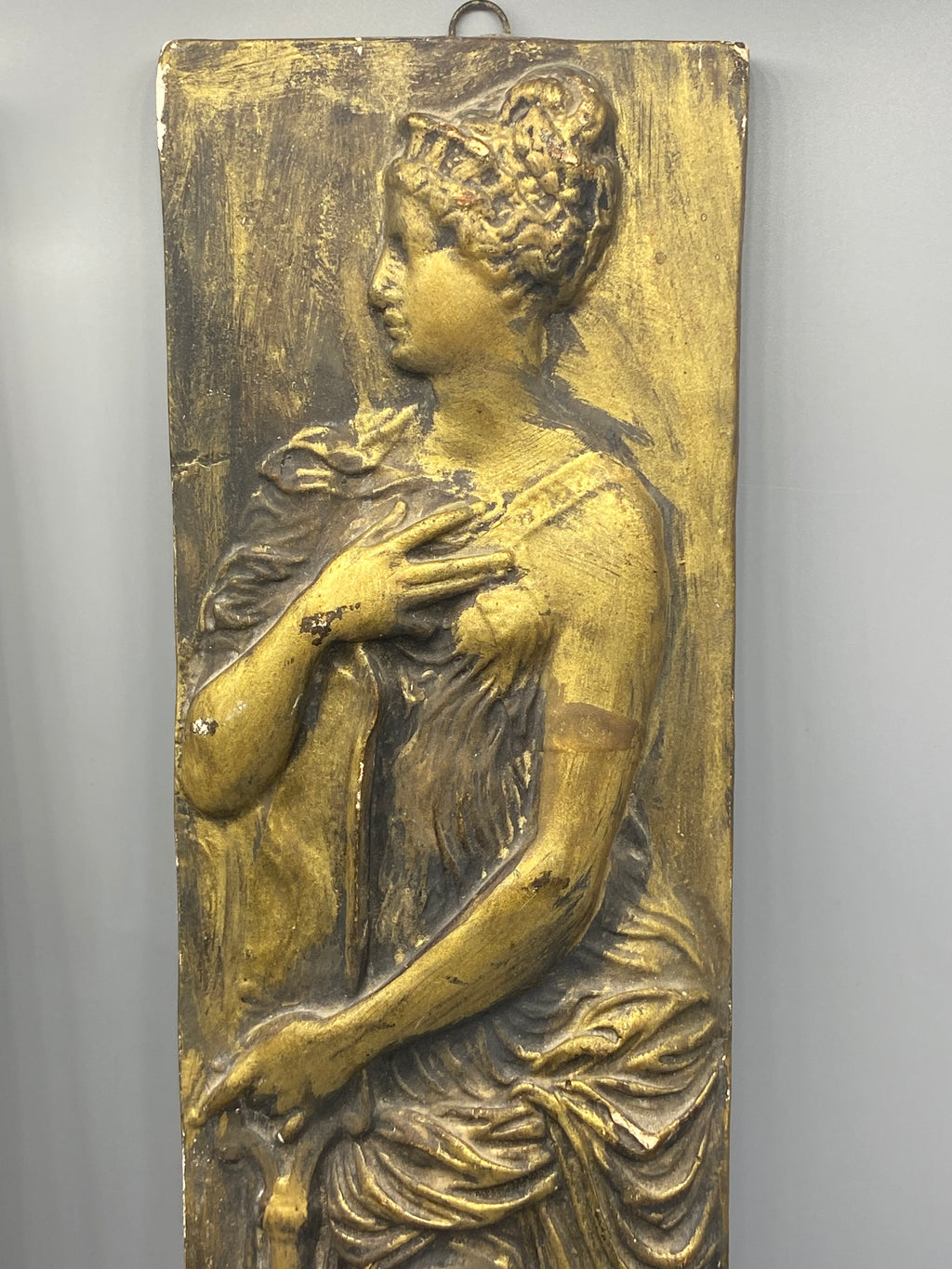Détail de l’usure de patine et des petits éclats sur le bas-relief