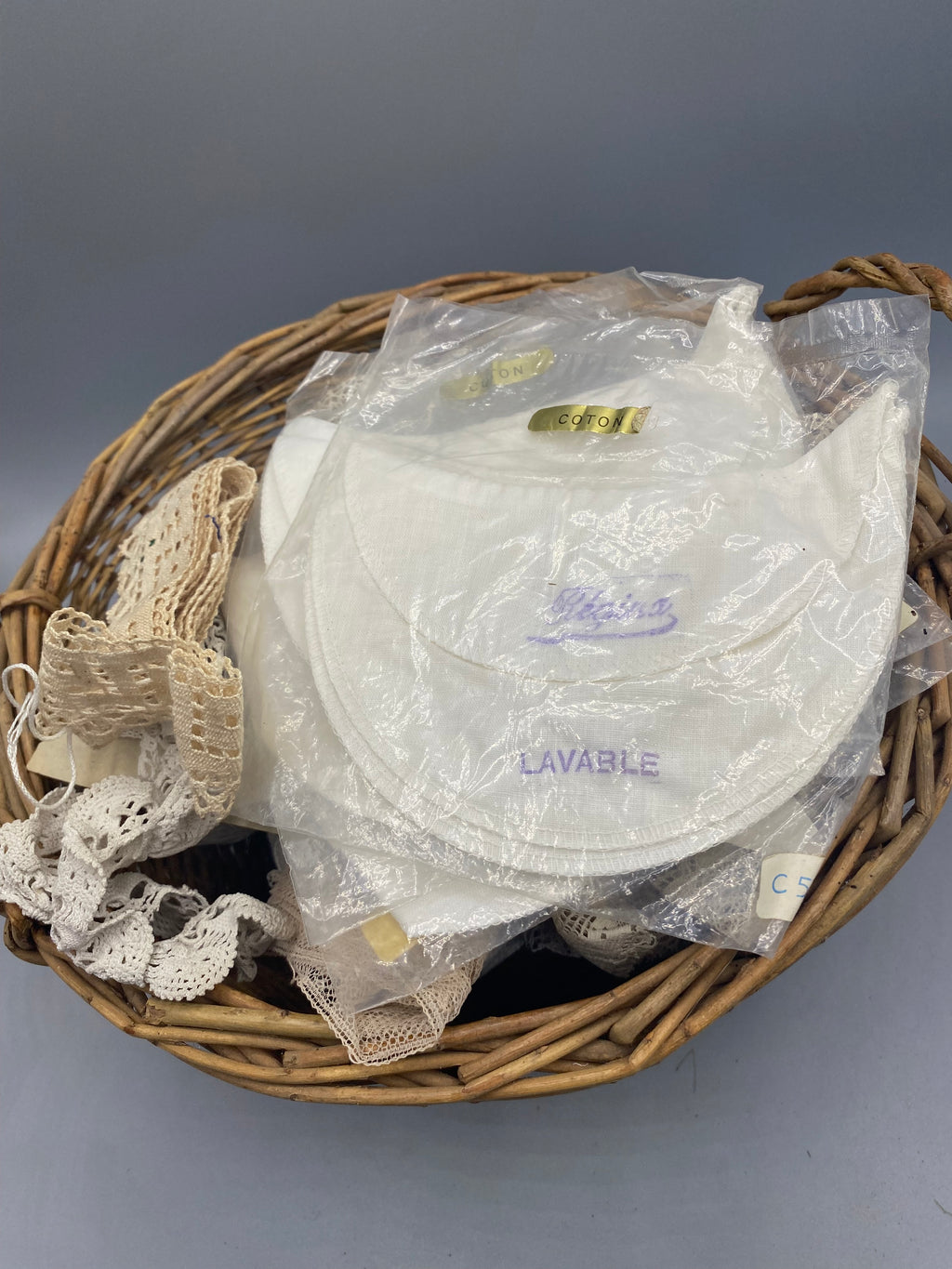 Ancien fonds de mercerie dans un panier en osier avec dentelles galons et fils