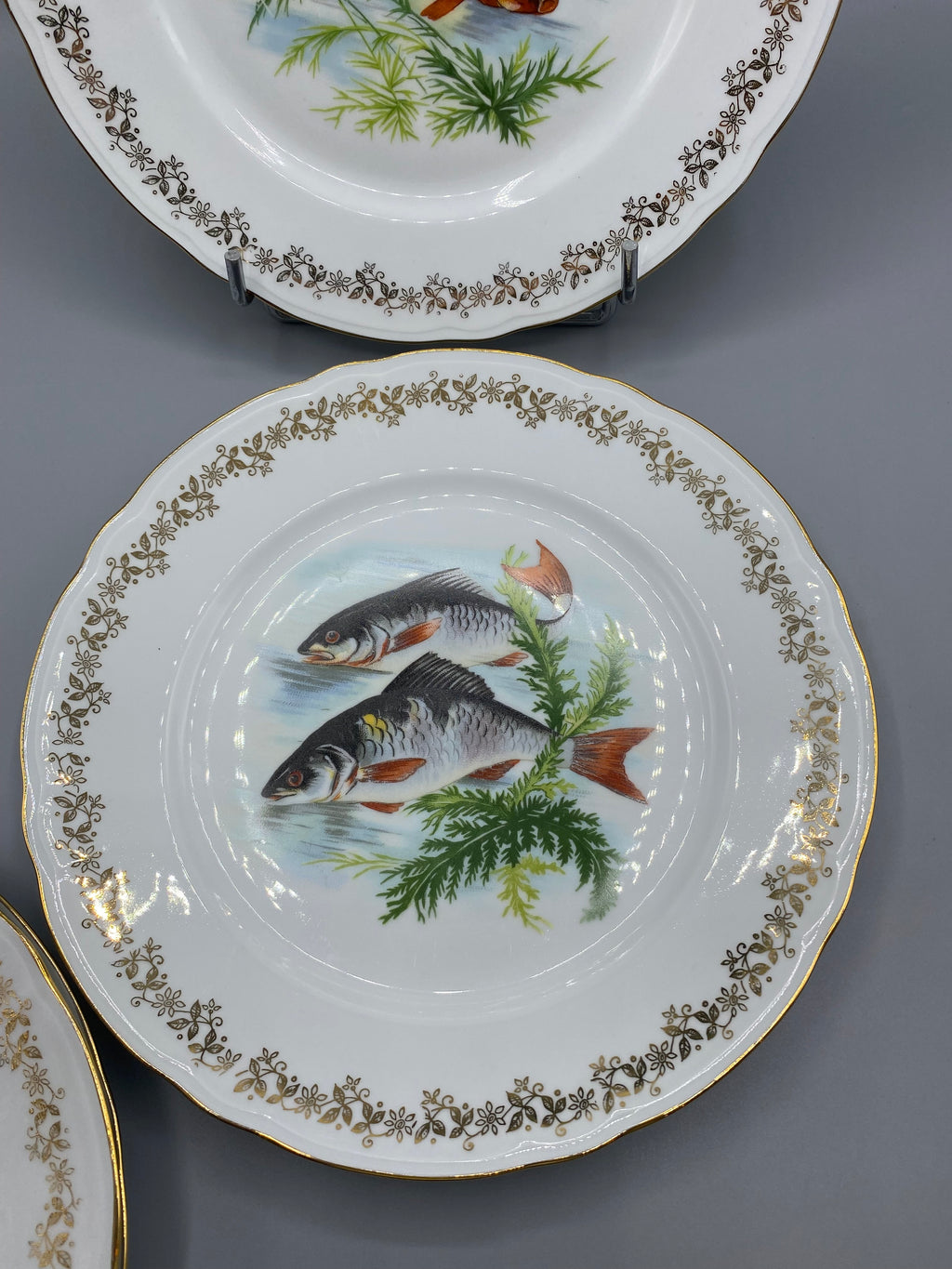 Assiette à décor de deux poissons et bordure florale dorée