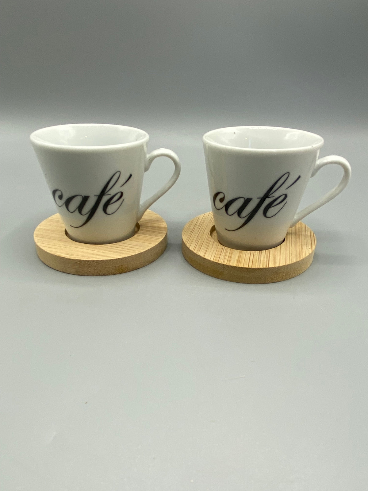Deux tasses expresso en céramique blanche avec inscription café noire sur leurs sous-tasses en bois