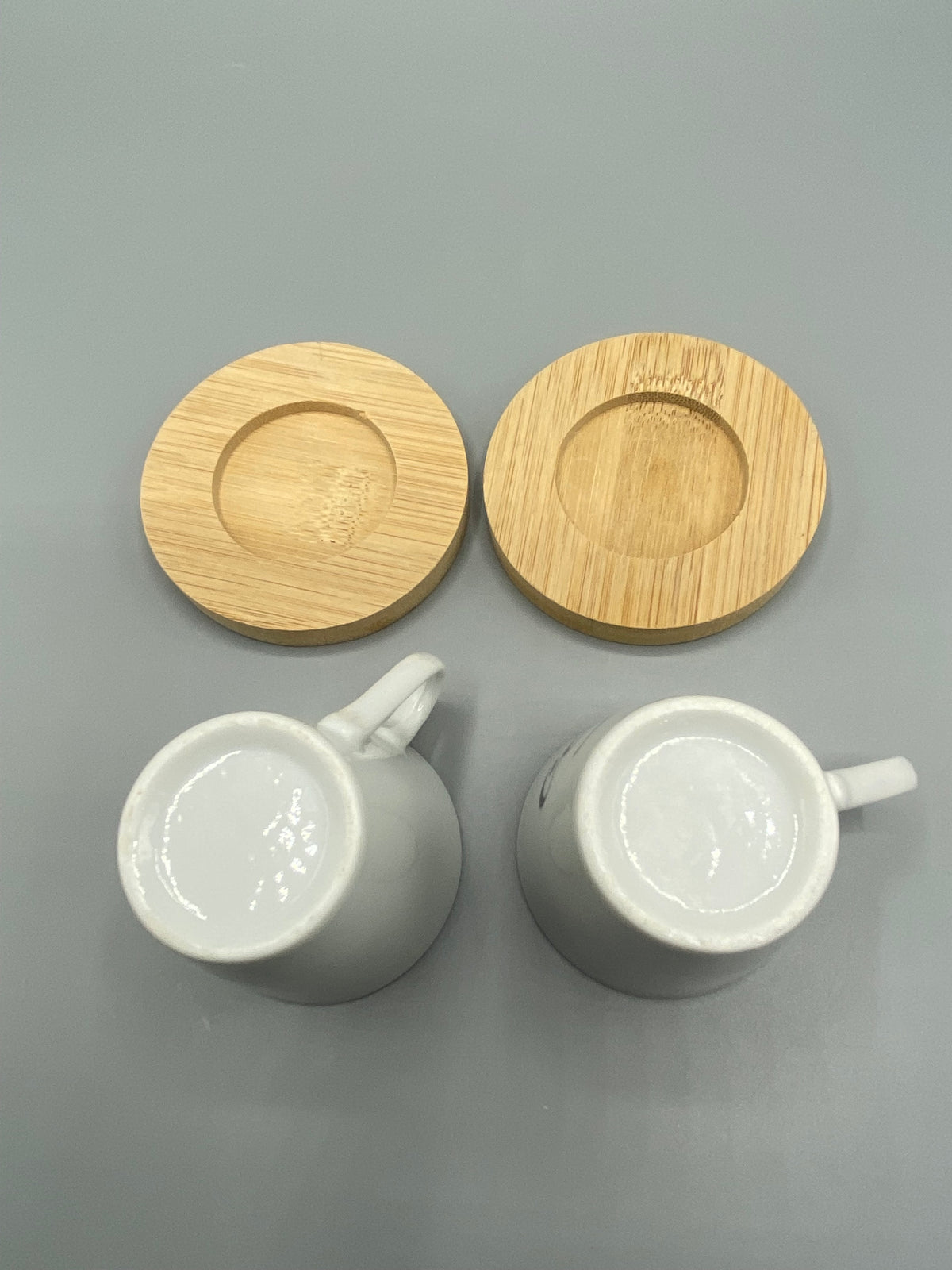 Dessous des deux tasses en céramique blanche et sous-tasses rondes en bois naturel