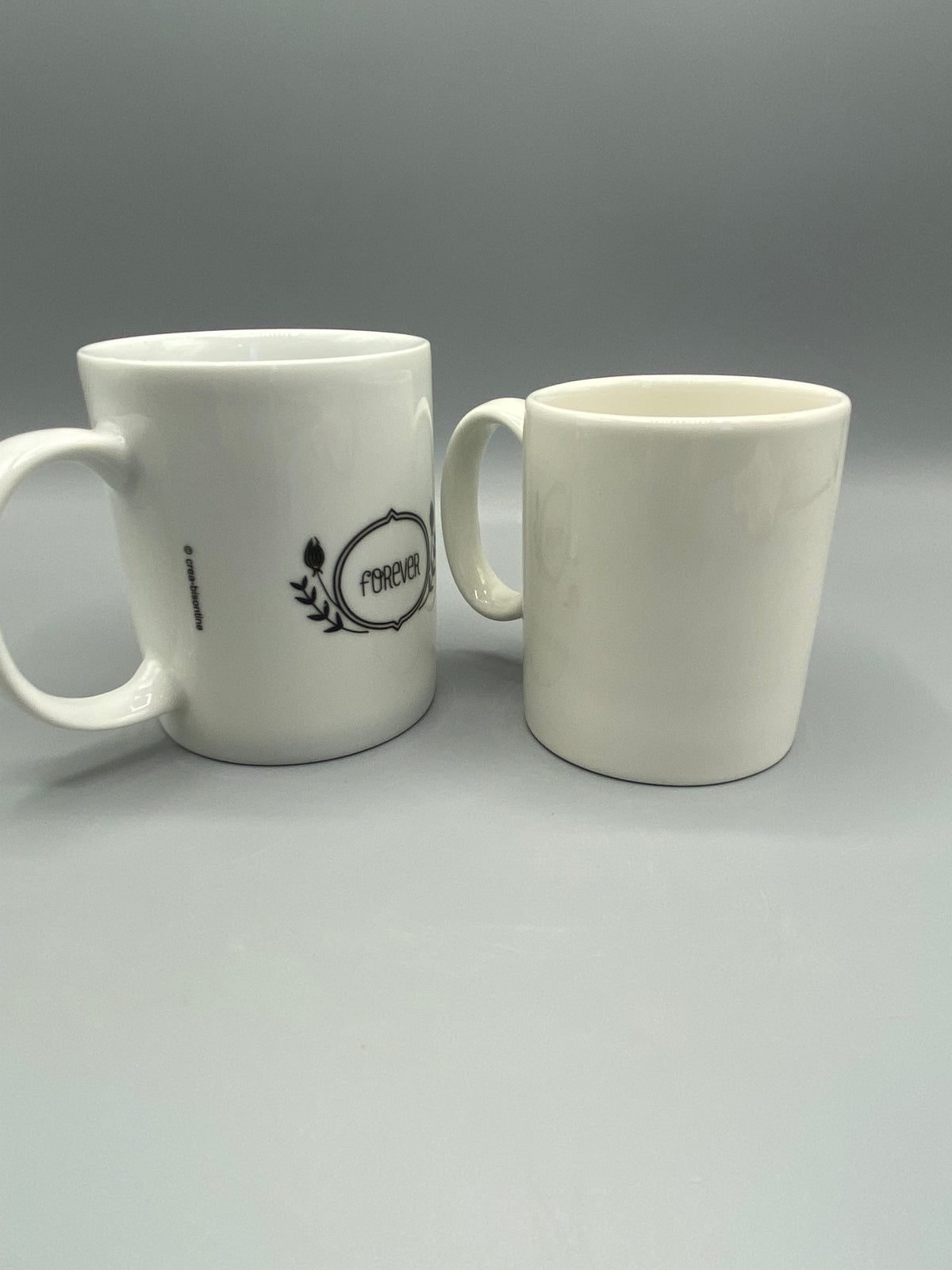 Deux mugs en céramique blanche à décor Super Marraine et colombe noire