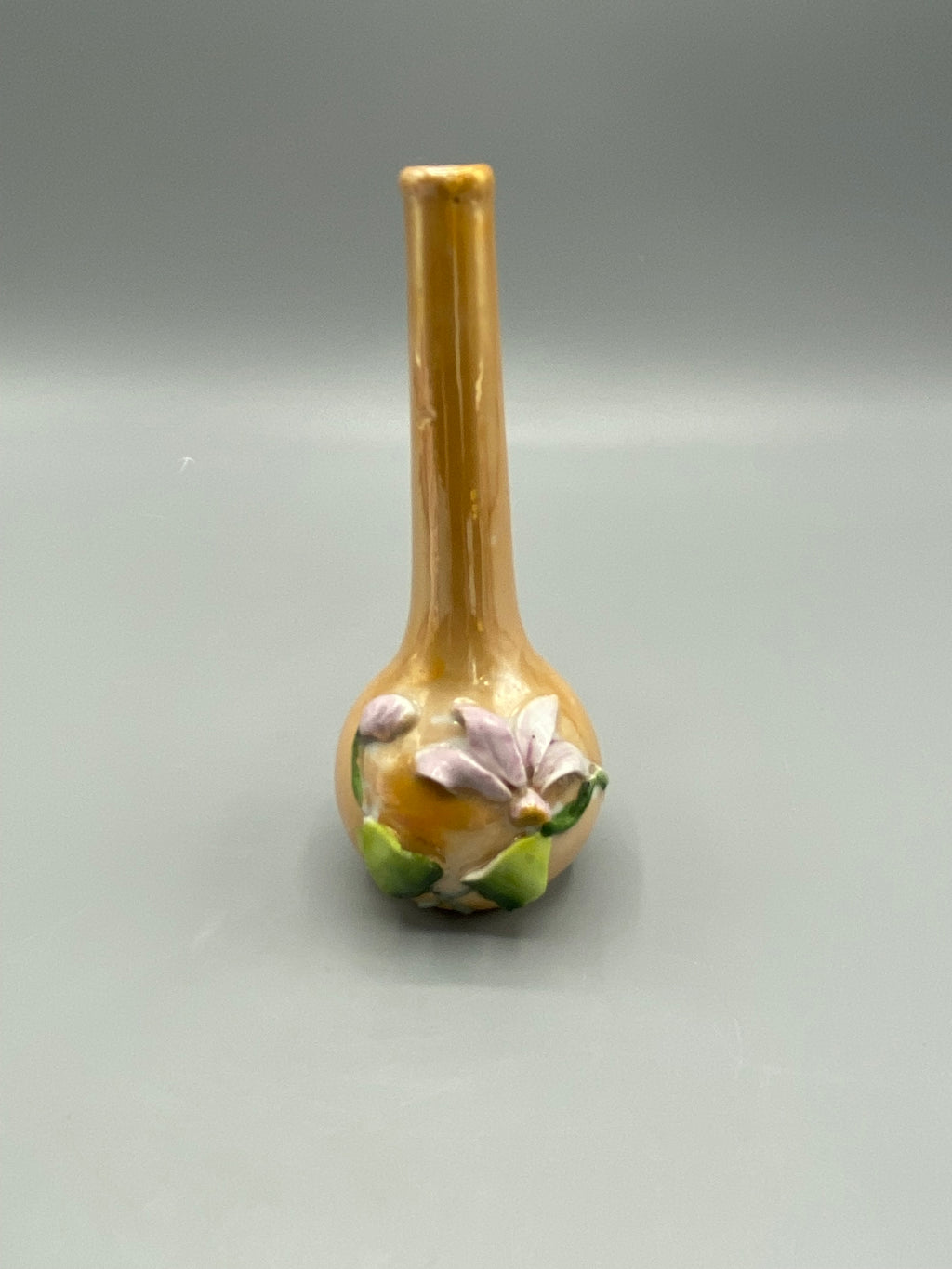 Détail de la fleur mauve et du feuillage vert en relief sur le vase miniature