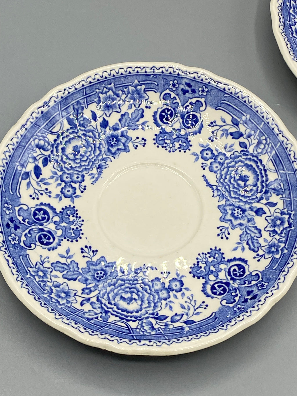 Détail du décor floral bleu et de la bordure festonnée d’une sous-tasse Burgenland
