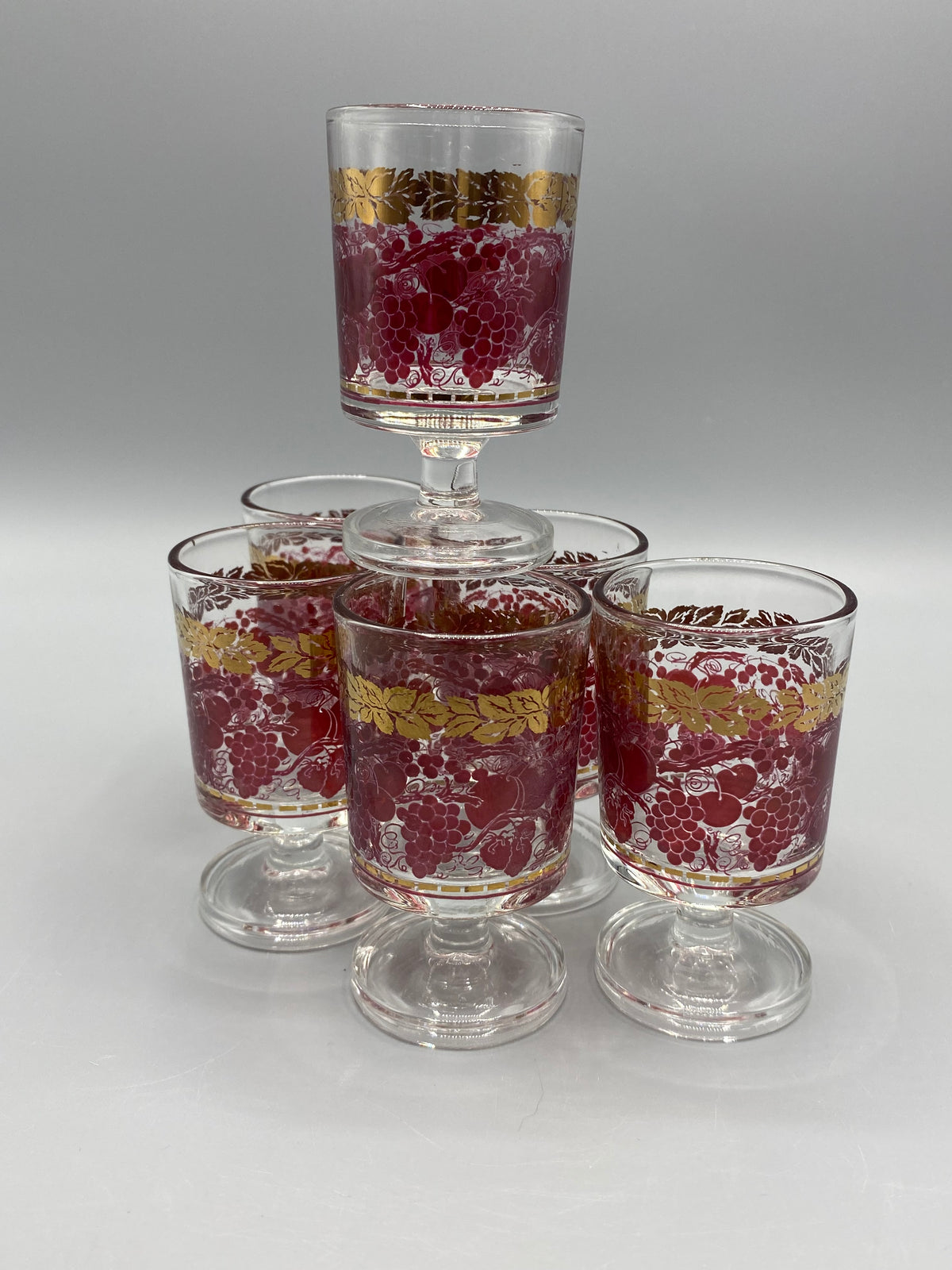 Détail du décor de raisins rouge rubis et de feuilles dorées sur un verre à liqueur