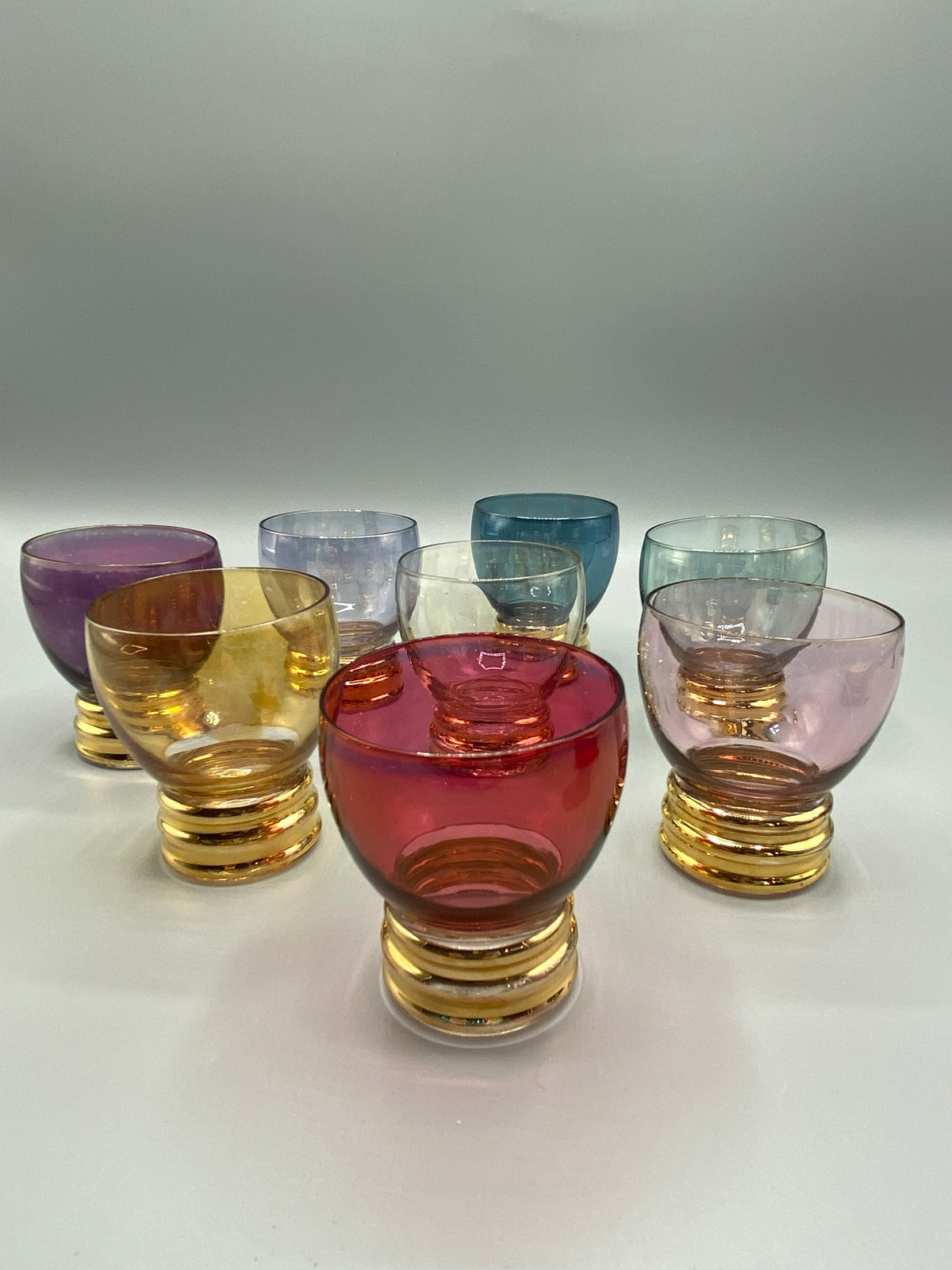 Verres à liqueur colorés et détail de la base annelée dorée d’un verre retourné