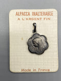 Petit médaillon Vierge Marie de forme florale en Alpacca argenté sur son cartonnage d’origine