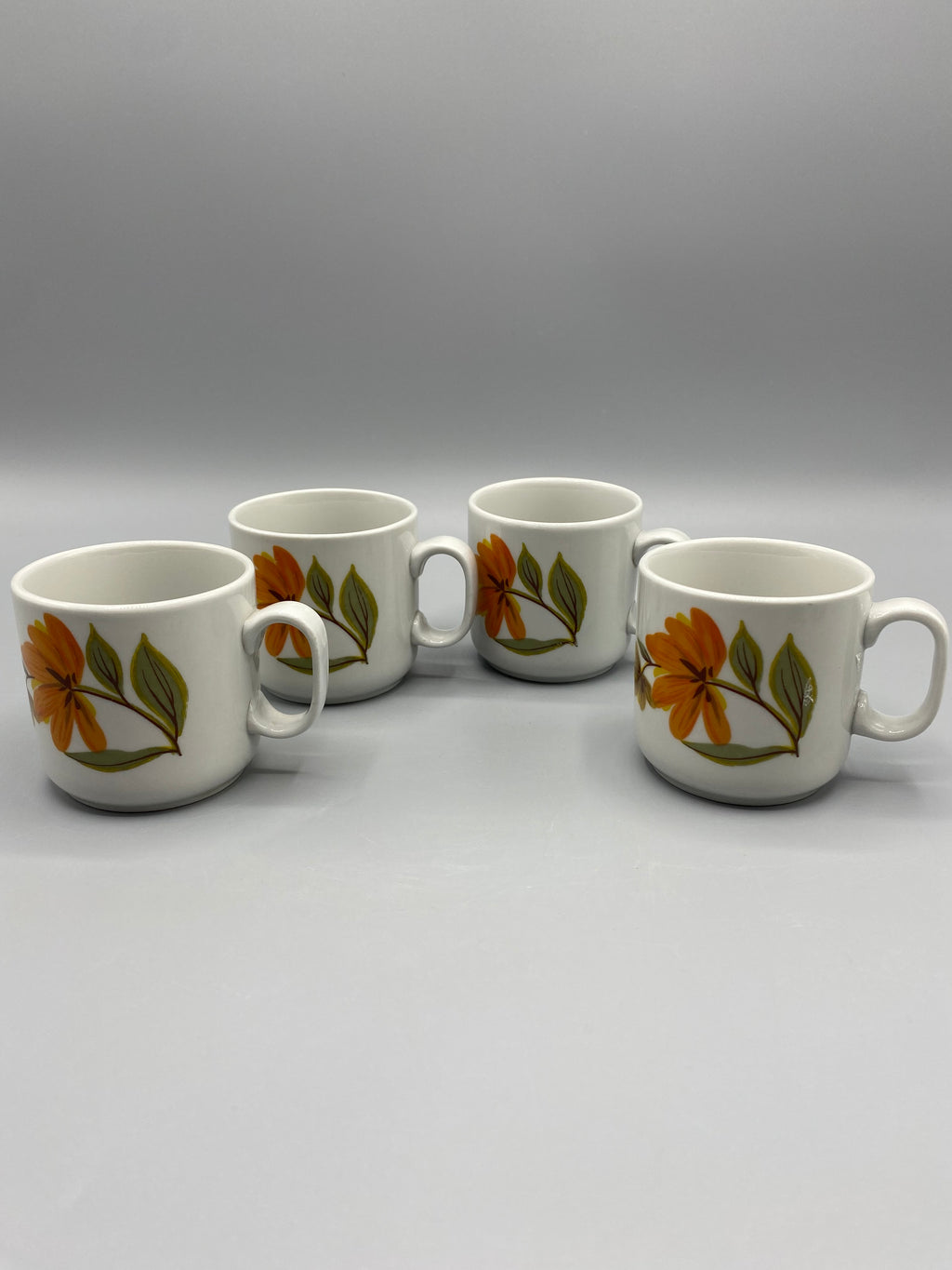 Détail du décor floral orange et du feuillage vert olive des tasses Monopoli