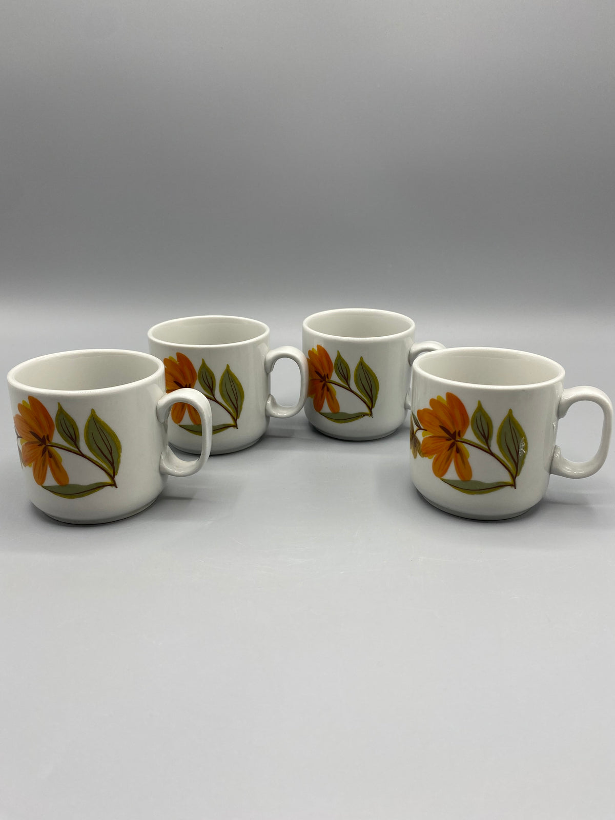 Détail du décor floral orange et du feuillage vert olive des tasses Monopoli