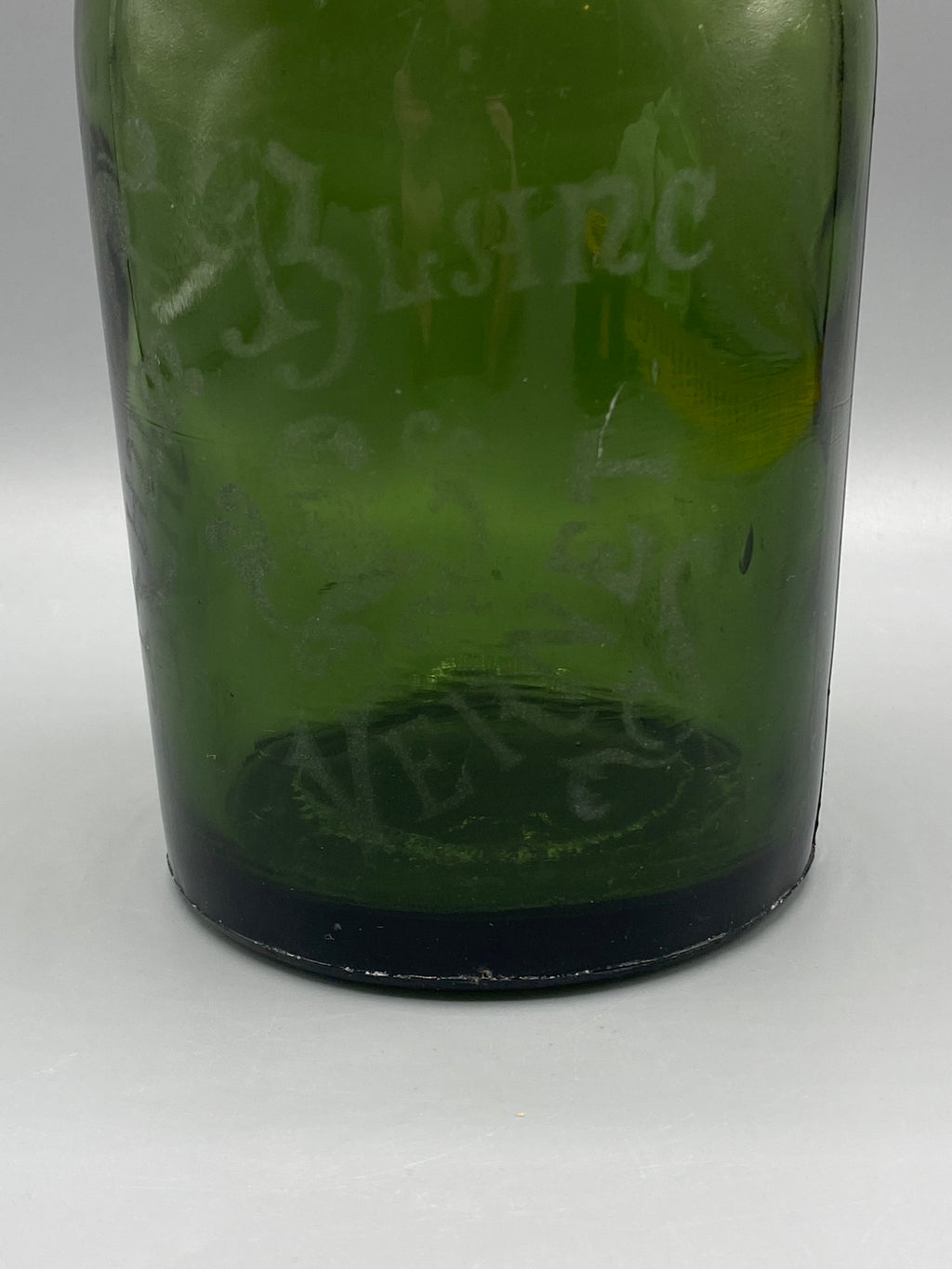 Détail des inscriptions anciennes sur le verre vert de la bouteille