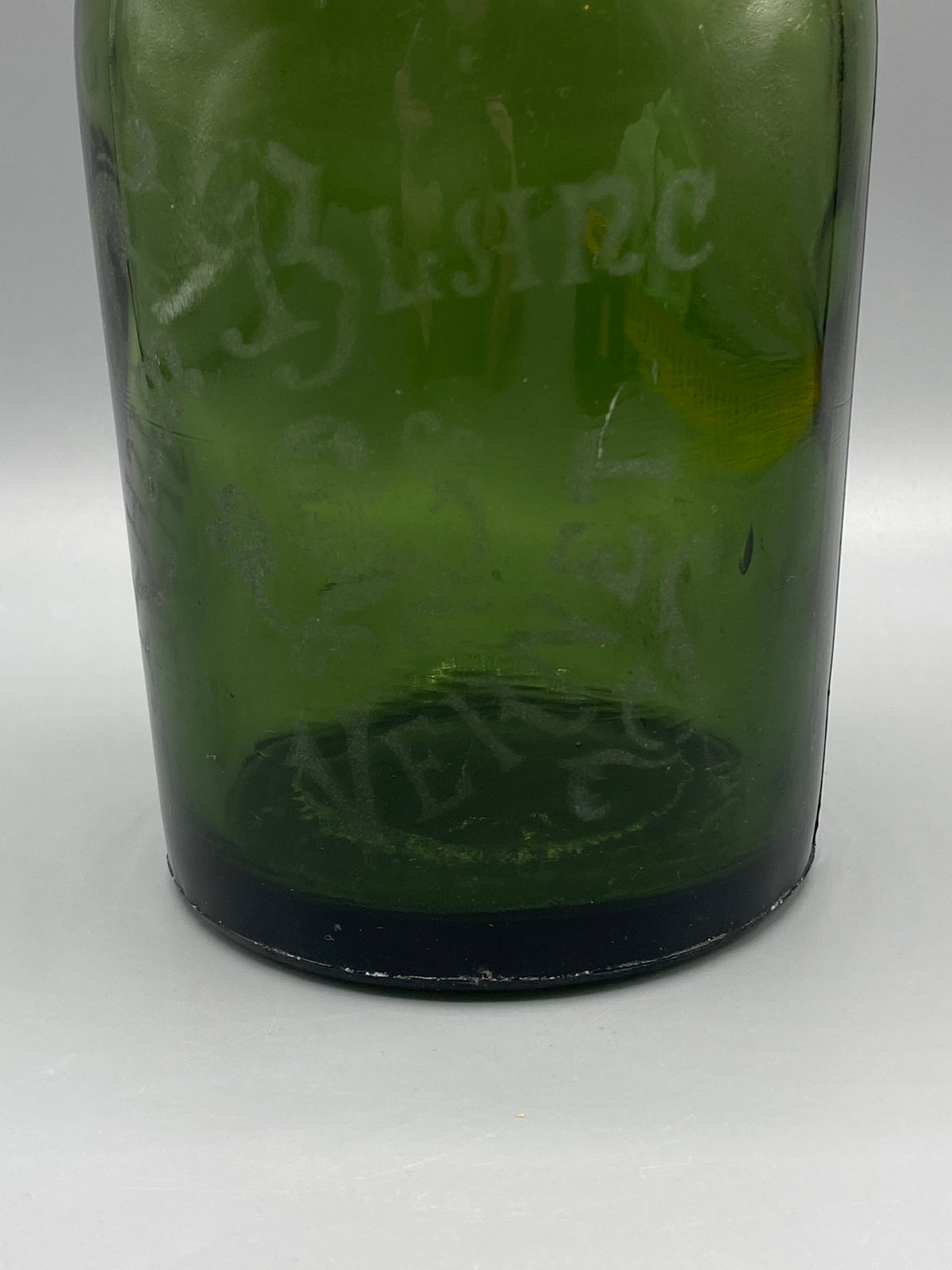 Détail des inscriptions anciennes sur le verre vert de la bouteille